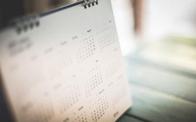 A spiral-bound calendar page is blurred at the edges. 